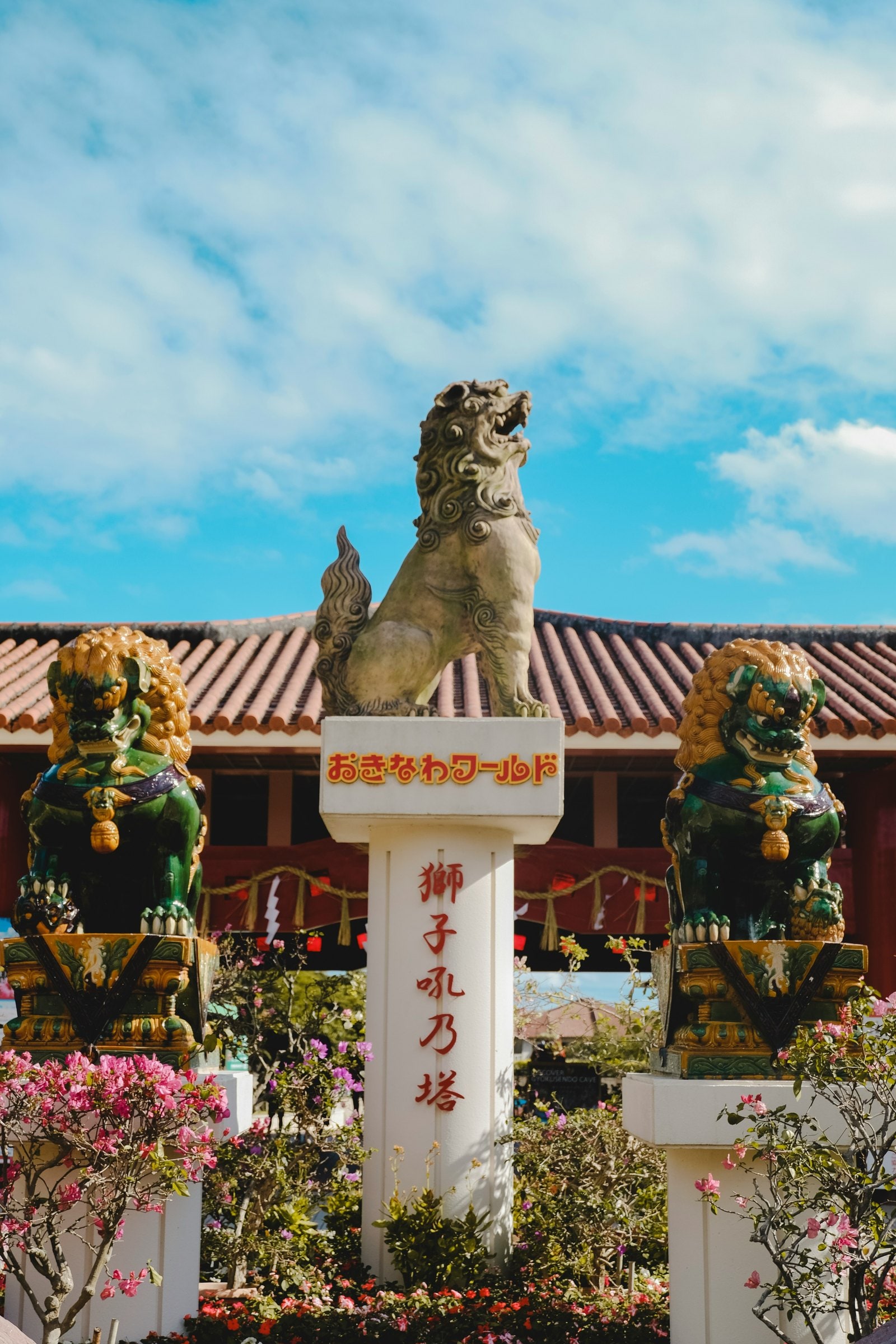 A shisa lion on a tiled gate under a blue sky — photo by T L, Unsplash